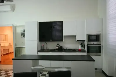 a kitchen with white cabinets and a black counter top at Irene's Home The Residence in Rome