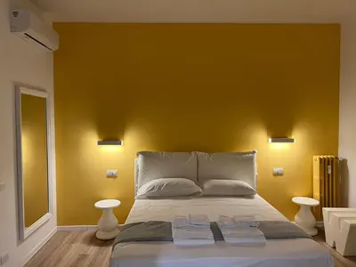 a bedroom with a large bed with a yellow wall at Roma Furio Camillo Holiday Home in Rome