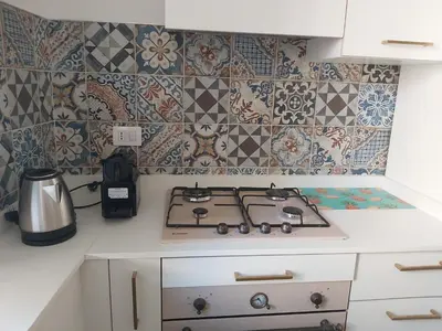 a kitchen with a stove and tiles on the wall at Roma Furio Camillo Holiday Home in Rome