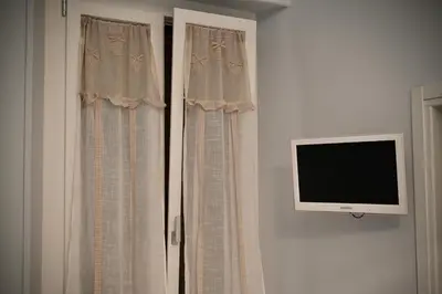 a window with a tv on a wall with curtains at Mirabilia Suites Colosseum in Rome