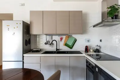 a white kitchen with a sink and a refrigerator at GuestHost - Porta Portese Modern Terrace Apartment in Rome