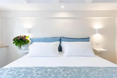 a bedroom with a white bed with a blue headboard at Pantheonview - Luxury Suites in Rome