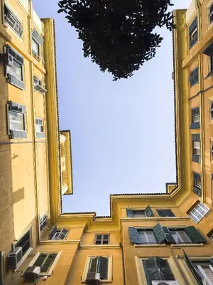 a tall yellow building with windows and a tree at St John Basilica Lovely Tower Apartment in Rome