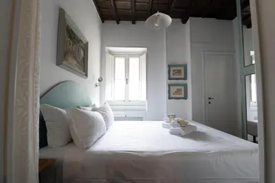 a bedroom with a bed with white sheets and a window at Al campanile Trastevere apartment in Rome
