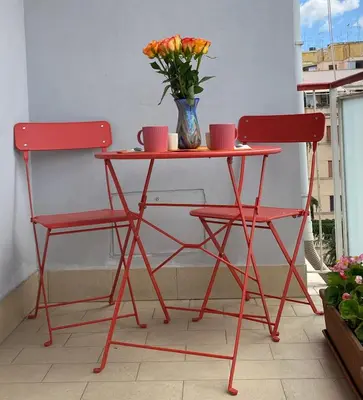 a red table with two chairs and a vase of flowers at Casa Fontana - zona San Giovanni Colosseo in Rome