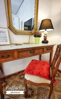 a table with a chair with a lamp and a mirror at Raffaello Apartment in Rome