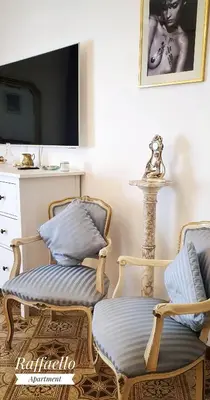 a living room with two chairs and a tv at Raffaello Apartment in Rome