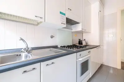 a white kitchen with a sink and a stove at St Peter House by Varental in Rome
