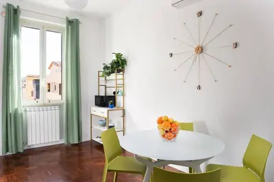 a dining room with a white table and green chairs at Idyllia - Bright and modern apt in Rome
