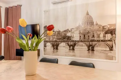 a vase of flowers on a table with a picture of the vatican at La Casa di Umberto in Rome