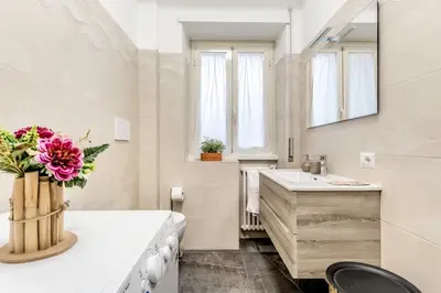 a white bathroom with a sink and a vase of flowers at La Casa di Umberto in Rome