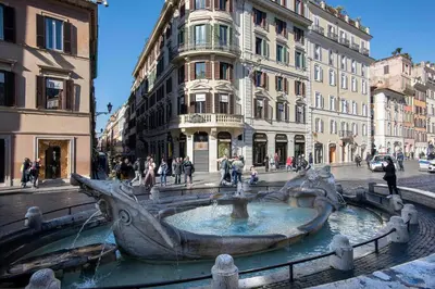 a fountain in the middle of a street with buildings at The Condotti - Luxury serviced apartment in Rome
