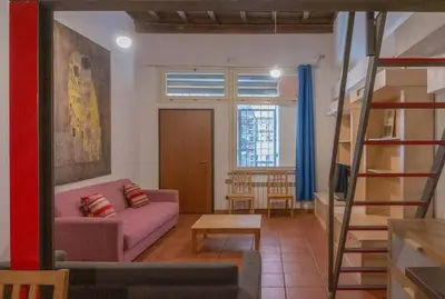 a living room with a pink couch and a ladder at Domus Reginella, nella zona più richiesta di Roma in Rome