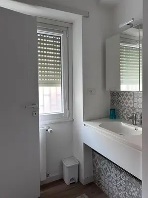 a white bathroom with a sink and a window at Otium - Tarquinia in Rome