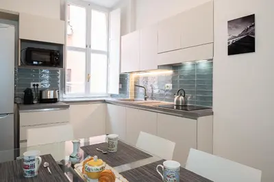a kitchen with white cabinets and a table at Jubilee apartment Vatican Museums in Rome
