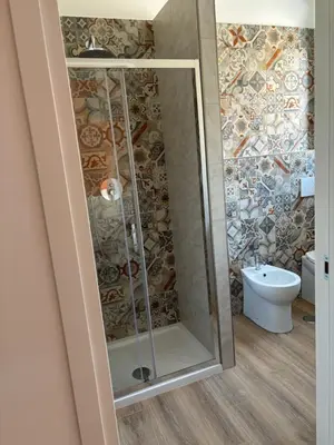 a shower in a bathroom with a mosaic wall at Suite and room in Rome