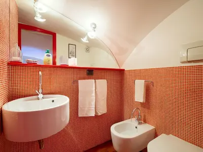a red tiled bathroom with a sink and a toilet at Sweet Home Colosseo in Rome