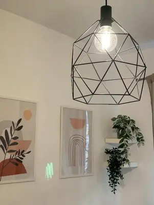 a light hanging from a ceiling with paintings and a plant at Saulo Guest House - A 10 minuti da Colosseo in Rome