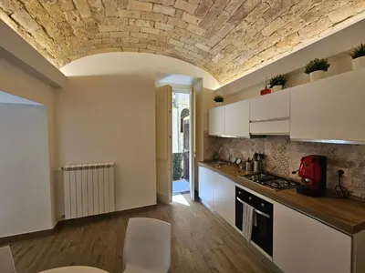 a kitchen with white cabinets and a brick ceiling at Campani Luxury Suite in Rome