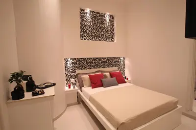 a small bedroom with a bed with white sheets and red pillows at Guesthouse Interno 7 Luxury Rooms in Rome