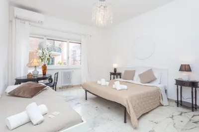 a white bedroom with two beds and a table at via Madonna del Riposo in Rome