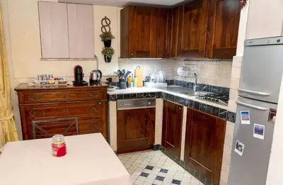 a kitchen with wooden cabinets and a white refrigerator at Colosseum Charming Loft - Santa Maria in Carinis in Rome