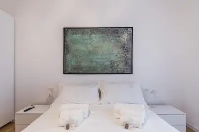 a bedroom with a white bed with a painting on the wall at THE FIFTH Properties Luxury Apartment near LUISS Rome Viale Libia in Rome