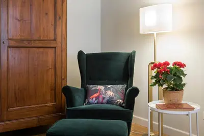 a green chair sitting next to a table with a vase of flowers at AV Domus Propaganda in Rome