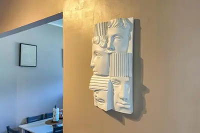 a wall mounted sculpture of heads on a wall at Cipro Vatican House in Rome