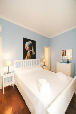 a bedroom with a white bed with a painting on the wall at Pettinari by BuddyRent in Rome