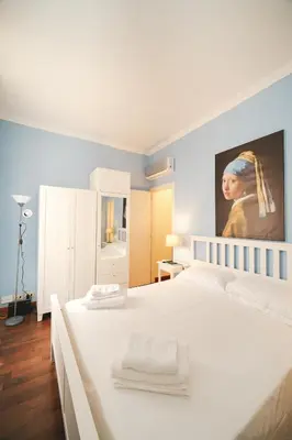a bedroom with a white bed with a painting on the wall at Pettinari by BuddyRent in Rome