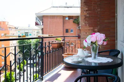 a table with a vase of flowers on a balcony at 81 mq, Stazione trastevere, Rome Sweet Home in Rome