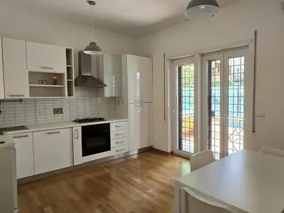 a kitchen with white appliances and wooden floors and windows at Roberta Rome Vatican Flat in Rome