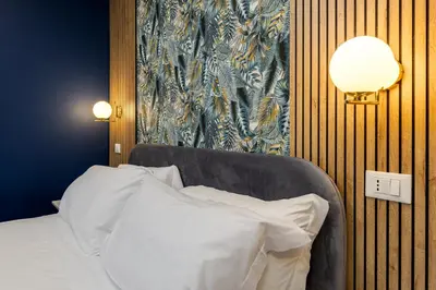 a bedroom with a bed and a lamp and a wall at NAIF Suites in Rome