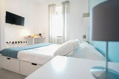 a white bedroom with a bed and a television at Salotto Tiburtino in Rome