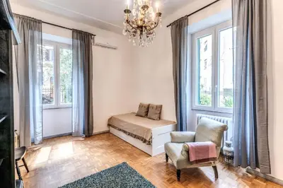 a bedroom with a bed and a chair and windows at Residenza Nemorense in Rome