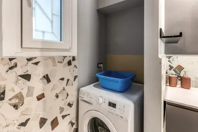 a laundry room with a washing machine with a blue bucket on it at Residenza Nemorense in Rome
