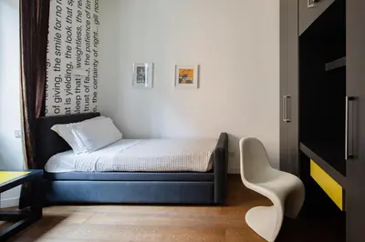 a small bedroom with a bed and a white chair at 2 bedrooms flat near Via Veneto in Rome