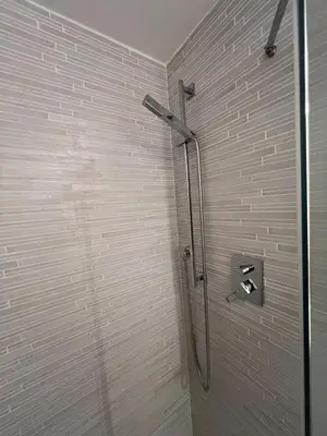 a shower in a bathroom with a white brick wall at La casa di Rosina al Pigneto in Rome