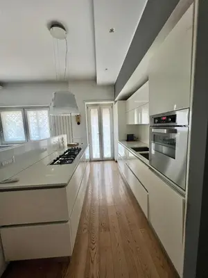 a kitchen with white cabinets and a wooden floor at La casa di Rosina al Pigneto in Rome
