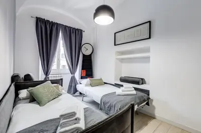 a bedroom with two beds and a clock on the wall at Clemente XII Repubblica House - 3 Bedroom Apartment in Rome