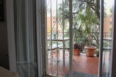 an open glass door to a balcony with a plant at Mary's Suite Aventino in Rome