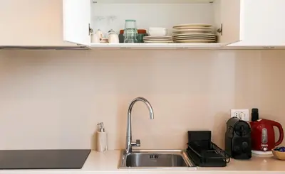 a kitchen counter with a sink and a cupboard with dishes at Bright Vatican Apartment in Rome