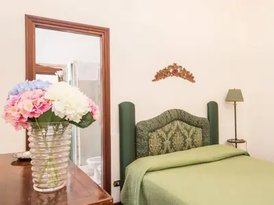 a vase with flowers on a table next to a bed at Luxury Apartment Spanish Steps in Rome