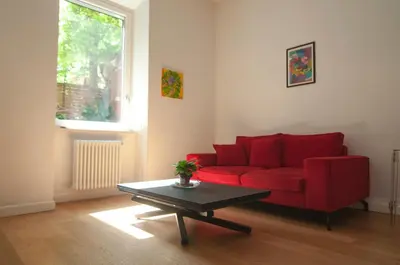 a living room with a red couch and a table at Perfect Hideout in Trastevere in Rome