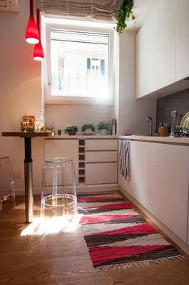 a kitchen with white cabinets and a red rug at Perfect Hideout in Trastevere in Rome