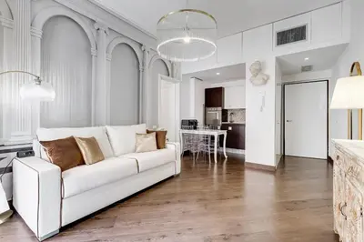 a living room with a white couch and a kitchen at NEXT TO SPANISH SQUARE - RomeDreamHome in Rome