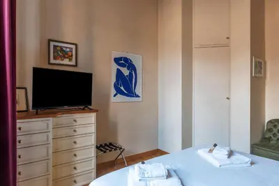 a bedroom with a television and a dresser with a bed at JOIVY Window on the Tevere in Rome