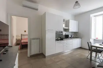 a kitchen with white cabinets and a table and a dining room at Vatican Cosy Apartment in Rome