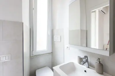 a bathroom with a sink and a toilet and a mirror at Vatican Cosy Apartment in Rome
